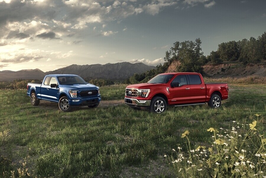 Image of a 2023 Ford F-150® XLT in Atlas Blue and F-150® LARIAT in Race Red parked on a mountain overlook