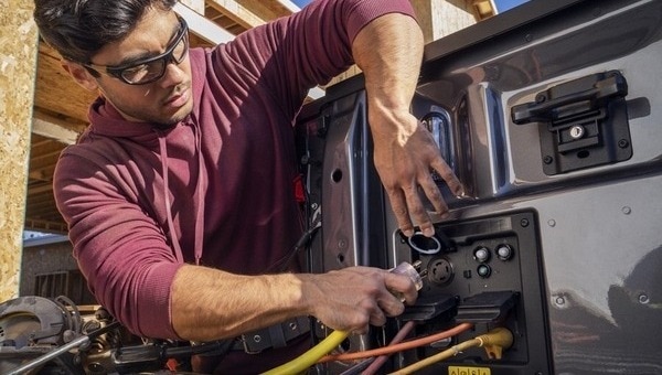 A 2023 Ford F one Fifty Pro with front trunk open parked at a job site