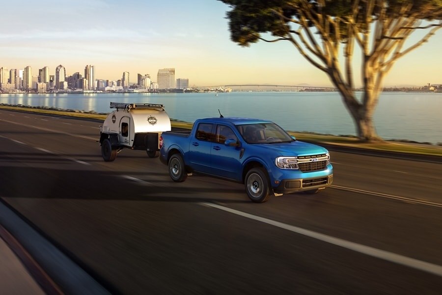 2023 Ford Maverick® LARIAT model with available 4K Tow Package hauling a trailer away from the city