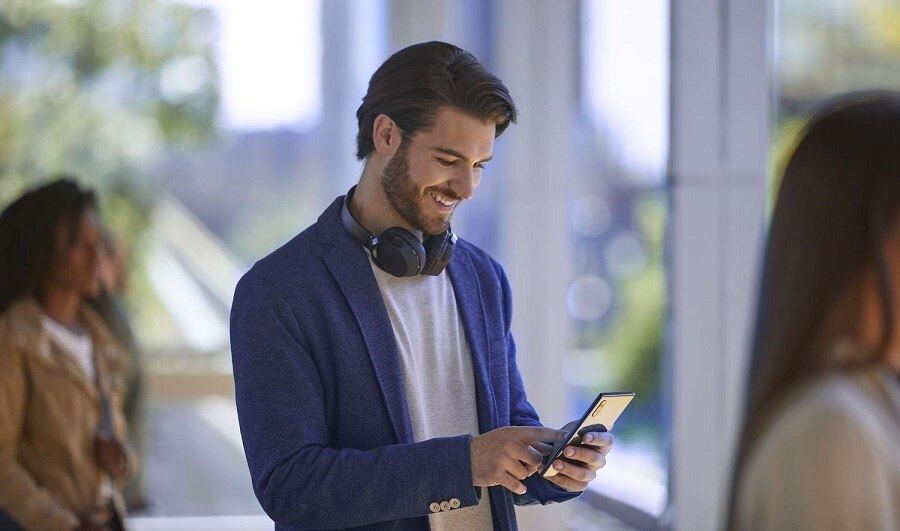 Man with headphones around his neck using his smartphone