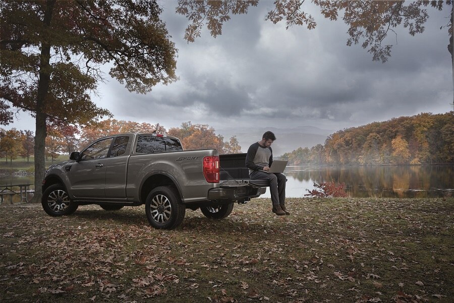 2023 Ford Ranger® SuperCab sport shown in carbonized gray with man using laptop on the tailgate