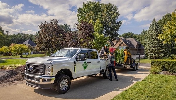 Ford Super Duty pickup truck parked on a grassy field during a work demonstration with two people standing nearby.