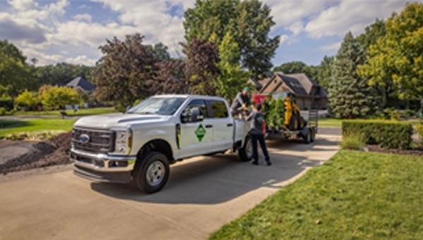 Ford Super Duty pickup truck parked on a grassy field during a work demonstration with two people standing nearby.