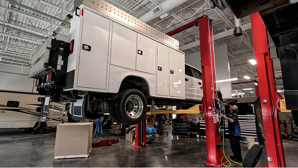 Ford truck on lift in large service bay for maintenance.