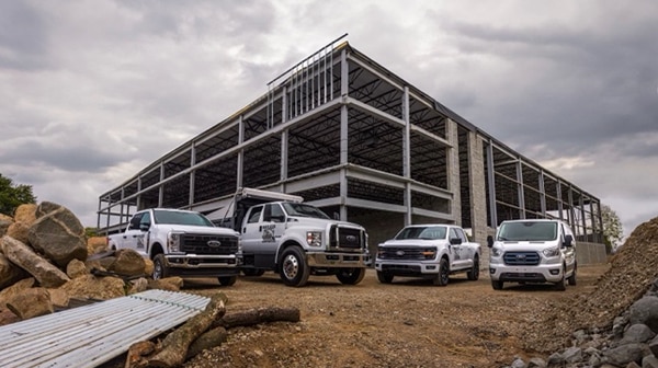 Four construction vehicles parked on a dirt lot.