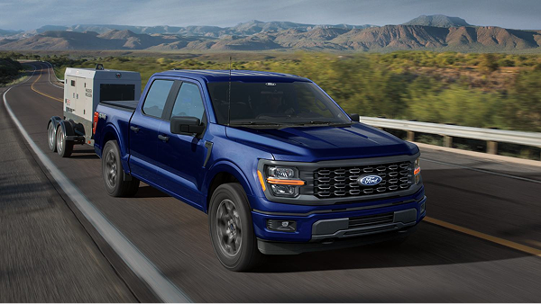 A blue 2026 F-150 pickup truck tows a generator on a highway.
