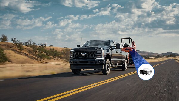 Image of a Ford F-250 XL towing construction equipment on a highway.