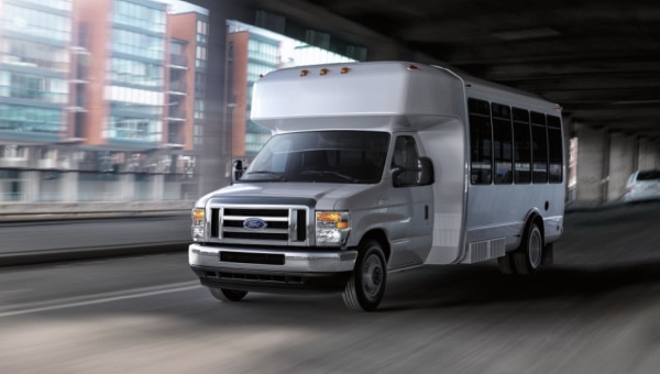 White shuttle bus in the city with a upfitter chassis.