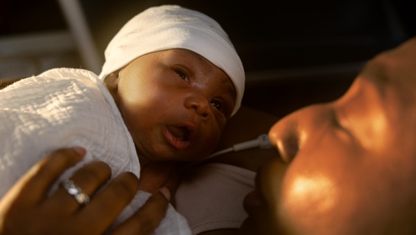 Close-up of a mother holding her newborn baby in a warm, intimate moment.