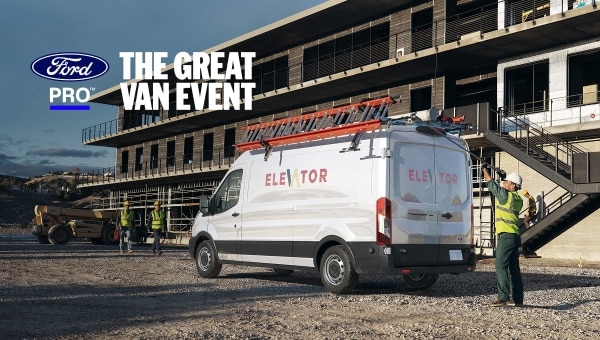White 2026 Ford Transit Medium Roof Cargo van with elevator company branding parked at a construction site, with workers in high-visibility gear nearby.