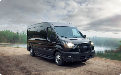 A black E-transit driving along a forested road.