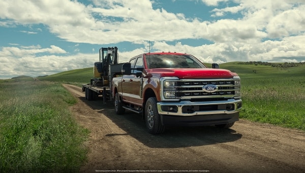 Ford Super Duty red truck close-up in green field under cloudy sky.
