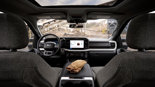 Wide interior shot from the rear seat showing the dashboard, infotainment screen, and center console.