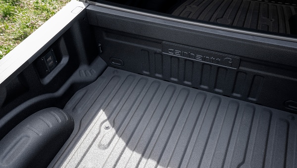 View of the truck bed featuring a protective liner and Carhartt branding on the front wall.